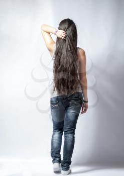 Back of young woman with long hairs, dressed in jeans. Isolated on white