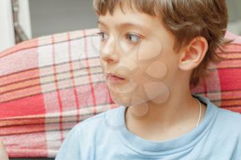 Portrait of an adorable young boy indoors sitting looking away.
