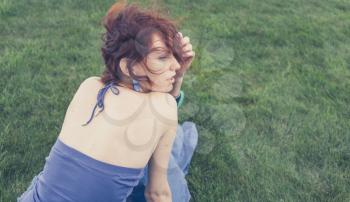redhead sitting on grass, backview, toned image
