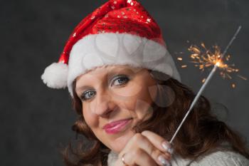 Closeup shot of the smiling women in santa hat. Cute girl in Santa hat holding sparklers