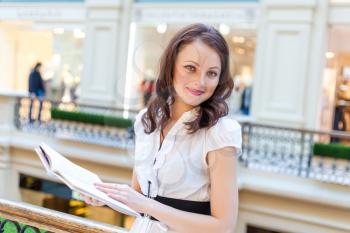 brunette holding book in her hands and looking at camera