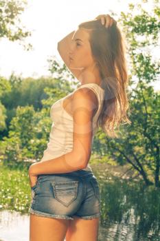Cute female weared jeans shorts. Back side of the female outdoors in summer time