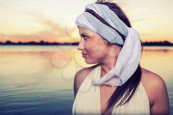 Profile view  on a retro hairstyle women against water and sunset