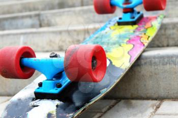 Vintage Style Colorful Skateboard with Red Wheels on a Street Stairs