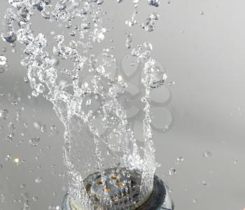 Shower head with water on gray and levitating drops of water in the air