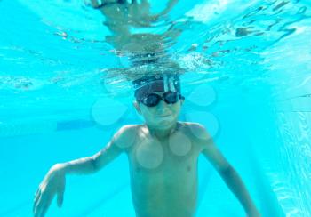 Portrait of a cute little boy swimming underwater in googles