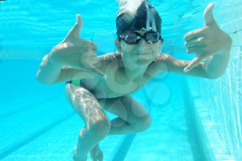Portrait of a cute little boy swimming underwater and making OK or Call-me sign by both hands