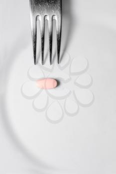 Silver fork and pink pill on the white plate, a lot of space for text