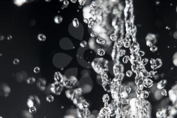 Drops of water levitating on dark with defocused drops on background