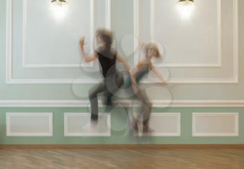 Happy couple jumping in front of decorative wall, motion blur toned shot with copyspace