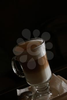 Latte coffee in transparent glass on dark background with copyspace vintage color-look