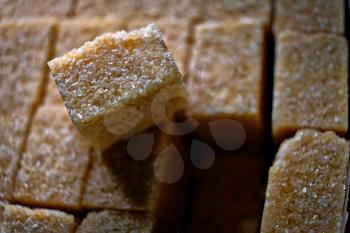 Close up shot of brown cane sugar cubes in pack, focus on one cube on the top extracted from bunch
