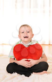 the child sit on the floor with a red plush heart