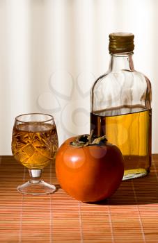 persimmon and a bottle of whiskey is on the table