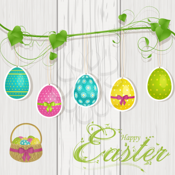 Easter eggs hanging from a green vine on a wood background with 'printed' Happy Easter message and basket of eggs