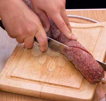 Royalty Free Photo of a Hand Cutting up Salami