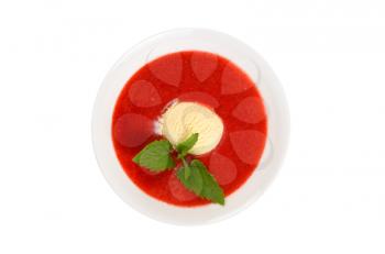 Strawberry soup with ice cream and mint on a white