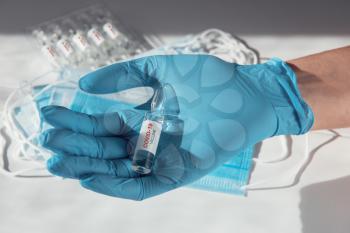 Coronavirus vaccine concept: covid-19 vaccine in hand with blue protective gloves.
