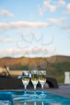 Three glass of cool champagne wine outdoor in a restaurant pool, terrace in mountain