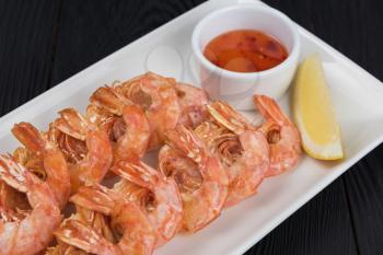Fried shrimps with sauce and lemon on plate