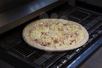 Preparing pizza in oven at restaurant kitchen