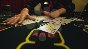 Casino stickman takes the cards from card holder at the game table