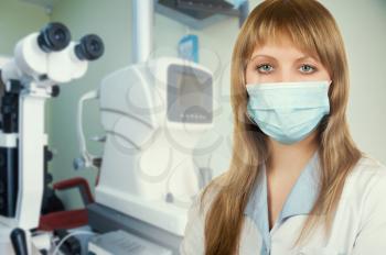 Female ophthalmologist in protective mask and whitecoat