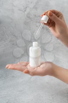 Woman hand with dropper bottle with white transparent liquid