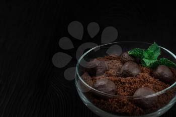Chocolate dessert of cookies with pieces of chocolate and mint on a dark wooden background.
