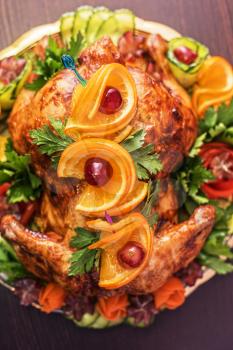 Whole roasted chicken with vegetables and fruits on wooden table