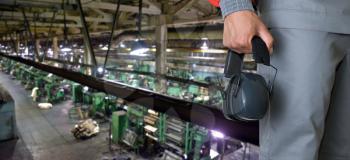 Worker with protective headphone at man hands at industrial factory