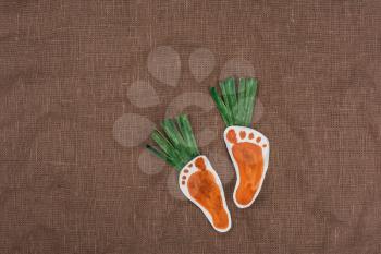 handmade foot-shaped carrot on sackcloth background