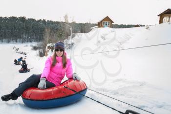 Young woman on a snow tube, at beauty winter day