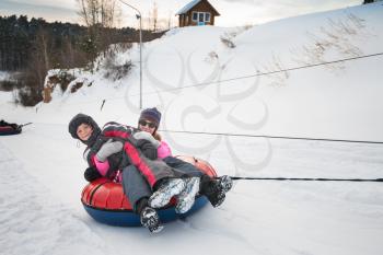 Mother and her son having fun on a snow tube, at beauty winter day