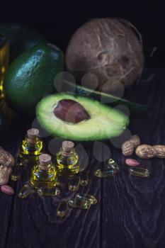 Oil of avocado with fish oil pills and peanut - source of omega 3 on a dark wooden background