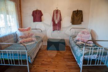 Old Slavic interior, bedroom with two beds, male and female clothes, and old box