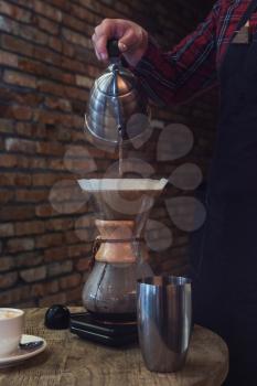 Barista brewing coffee in chemex in the cafe