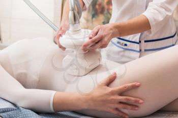Woman in special white suit getting anti cellulite massage in a spa salon. LPG, and body contouring treatment in clinic. Lipomassage procedure on female body.
