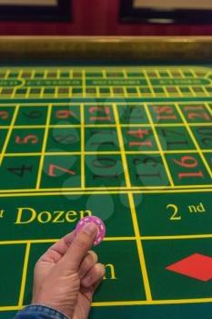 Casino, gambling and entertainment concept - male hand with stack of poker chips on a green table background