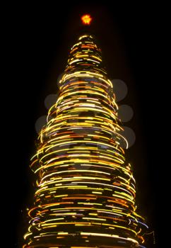 Blurred rotating Christmas tree at night over black