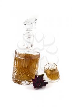 Crystal decanter with jigger and flower for alcoholic beverage over white