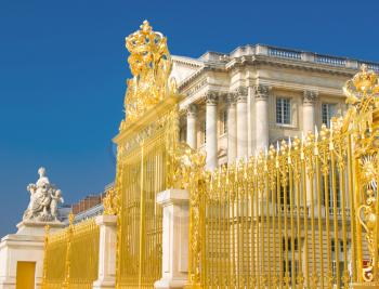 Golden gate and Palace facade in Versailles over blue sky. France