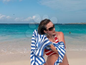 A beautiful young female is drying her hair with the towel on the caribbean beach.