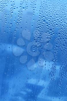Blue background with water drops on glass