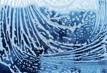 Bright blue abstract texture with soap foam pattern on glass