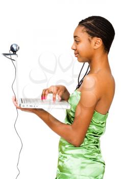 Royalty Free Photo of the Profile of a Teenage Girl Using a Laptop with a Webcam