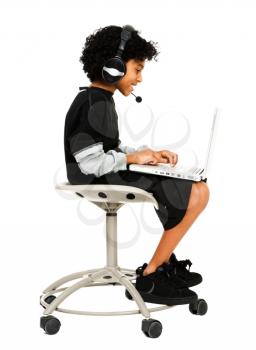 Royalty Free Photo of a Young Boy Sitting in an Office Chair Using a Laptop Talking on a Headset