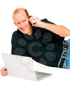 Royalty Free Photo of a Man Using a Laptop and Talking on a Mobile Phone