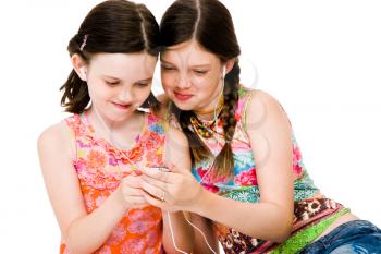 Sisters listening to MP3 player and smiling isolated over white