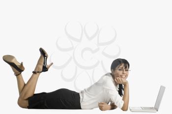 Woman lying in front of a laptop and smiling